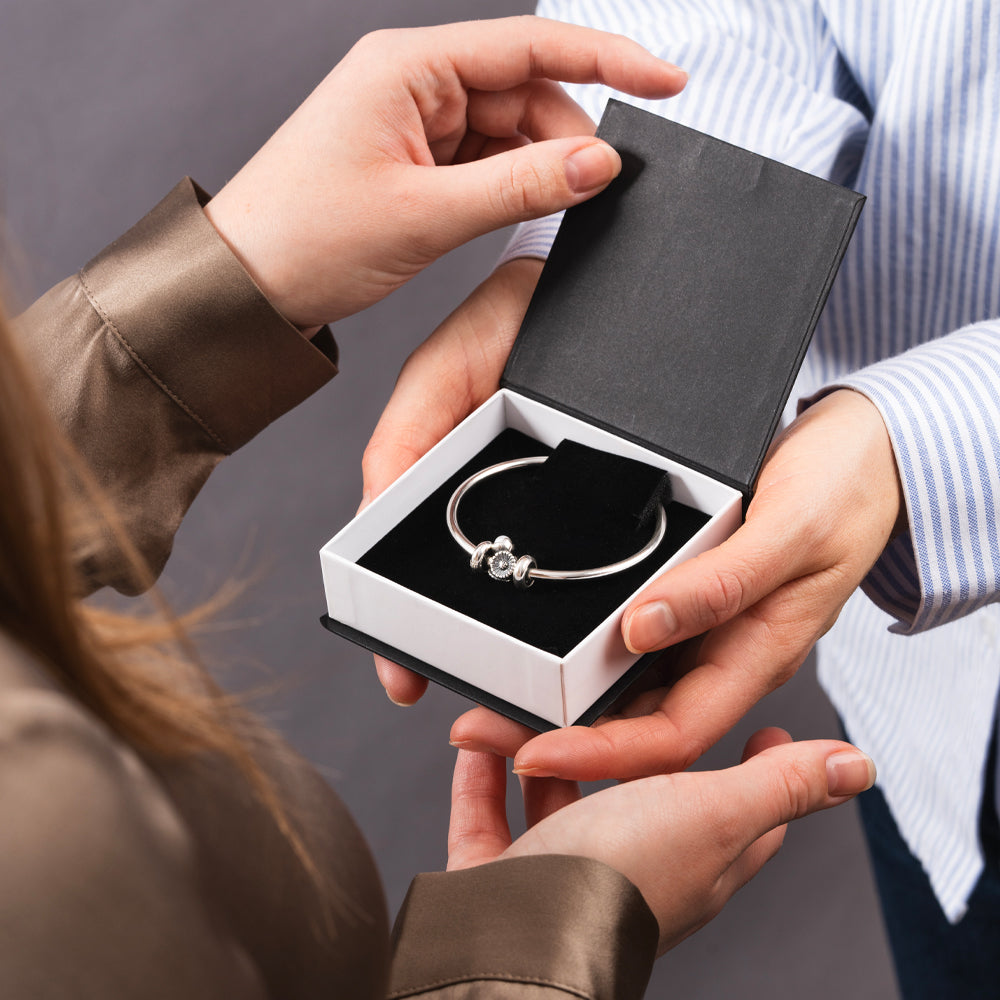 Person holding a Trollbeads gift box with silver bangle with silver flower bead