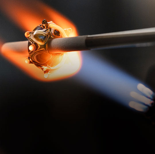 Glass bead being made over a red hot flame